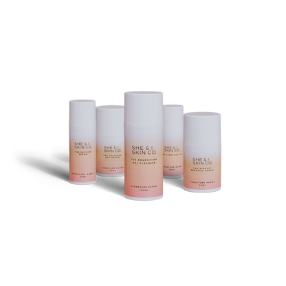 She & I Skin Co. skincare collection featuring cleansers, creams, and serums in sleek white-to-pink gradient packaging, perfect for a nourishing and luxurious skincare routine.