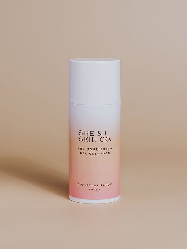 She & I Skin Co. "The Nourishing Gel Cleanser," 100ml, formulated to gently cleanse and hydrate the skin. Displayed in sleek gradient white-to-pink packaging on a minimalist beige background.