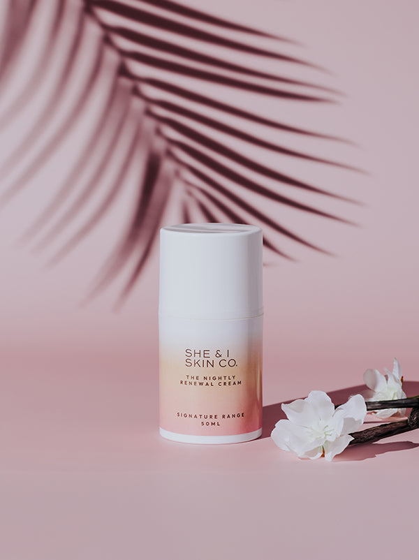 She & I Skin Co. "The Nightly Renewal Cream," 50ml, elegantly displayed with white flowers and palm shadows, evoking a soothing, tropical vibe for luxurious nighttime skincare.